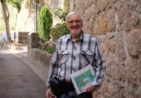 Karl Hermann Gutheil steht bei einer Führung auf Schloss Dhaun mit einer Dokumentenmappe vor einer historischen Mauer.