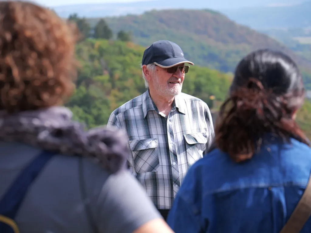 Karl Hermann Gutheil spricht bei einer Führung auf Schloss Dhaun mit Besuchern vor der Landschaft des Hunsrücks.