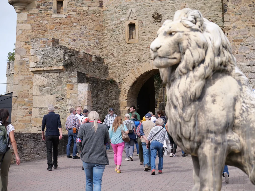 Eine Besuchergruppe steht bei einer Führung vor dem historischen Eingang von Schloss Dhaun, während Karl Hermann Gutheil die Gruppe führt.